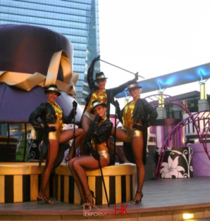 4 dancers in front of giant hat prop at a mall in Hong Kong
