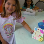 A girl  is showing off her own designed photo frame make in a children birthday party