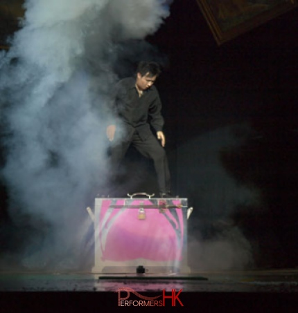 Magician standing on a huge pink box performing stage magic at a corporate annual dinner