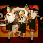 Three walk around musicians drum sax and tuba donning German attire and posing