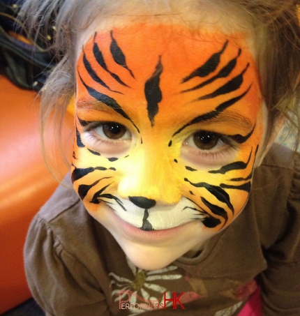 Face painter in HK draw a lion face painting with orange , yellow and black at a kids birthdays party