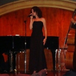 A Hong Kong Singer standing in front of a piano and a cello,  performing at corporate annual dinner