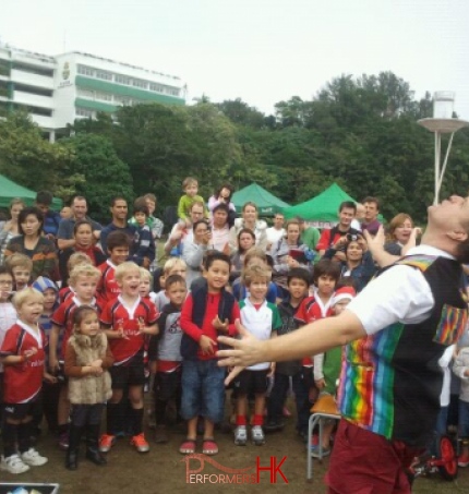 Performer balancing a glass of water on three chopstick whilst a large crowd watches