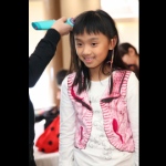 A little girl getting second braid wrap with a colorful string at a school event