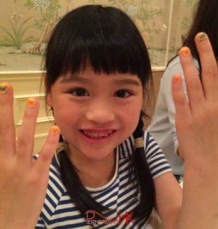 The little girl is showing off her nail art with a happy face at a kids birthday event