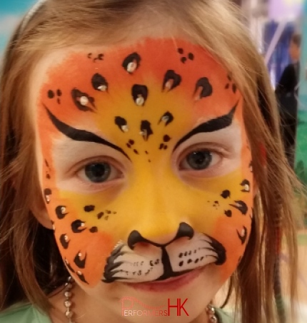 A Face painter draw a leopard face paint with sparkle sticker on a little ladys face at a kids store opening event