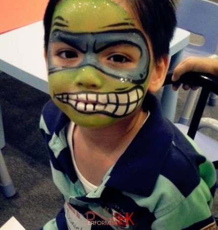 HK best face painter paint a scary green and blue monster face paint for a kids at a corporate Halloween event. 
