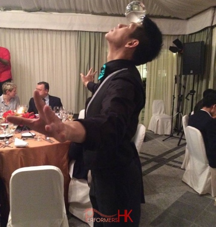 Roving juggler in Hong Kong holding a crystal ball on his head with out using his hands at a corporate cocktail party