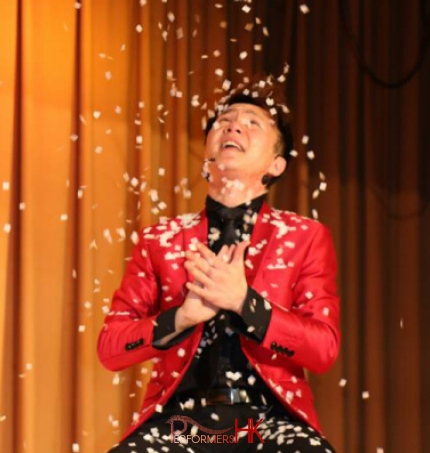 Hong Kong Magician wearing a red jacket performing snow storm magic trick at a corporate annual dinner 