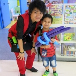 Walk around balloon twister twisted a blue and purple gun to a kid at a Hong Kong Corporate store opening event