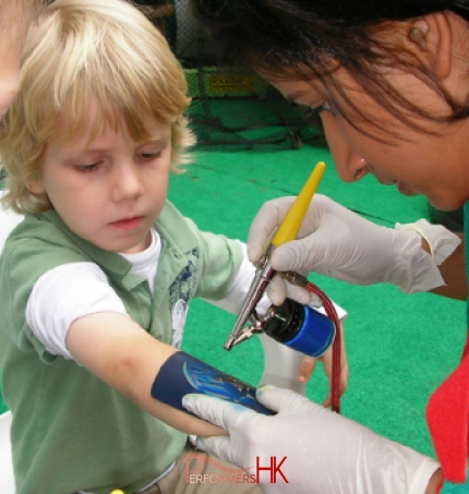 The Temporary tattoo artist in Hong Kong spraying a tattoo on a child arm