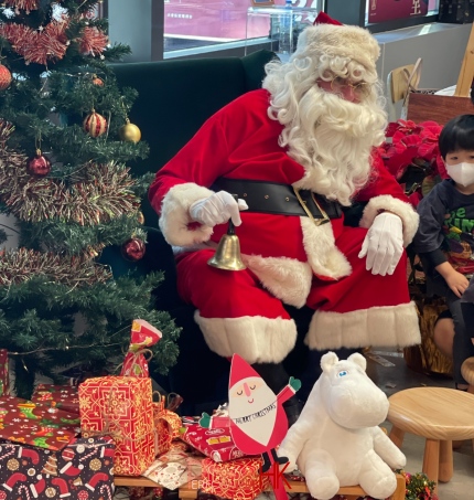 Santa sitting in front of a Christmas tree in Central market Hong kong with a kid next to him