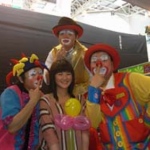 Tony and other clowns poses with a female guest holding her balloon and pressing their noses. 