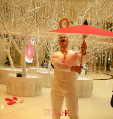 Juggler wearing white , juggling with umbrella and ring at a Hong Kong Christmas corporate event