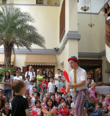Performer doing a juggling trick in front of kids audiance