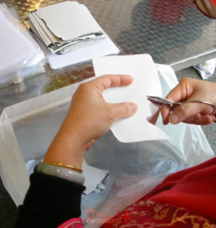 Portrait cutout artist with scissors demonstrating her wares