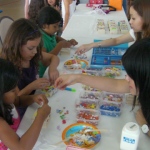 Two staff is assisting the children to decorate their own crafts at a corporate event