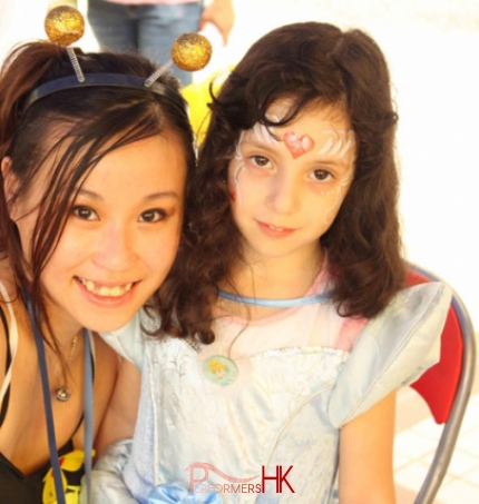 Face painter posing with child wearing princess makeup