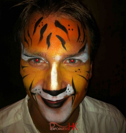 A Face painter in Hong Kong draw a tiger for a gentleman at a adult safari themed event
