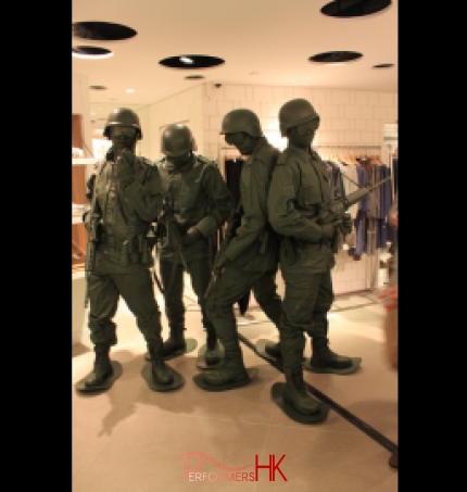 Four human living statue toy soldiers standing in a clothing shop