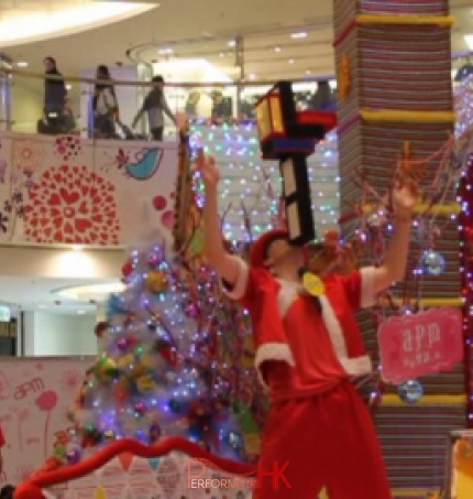 HK juggler performing at a corporate shopping mall event ,  holding six cigar boxes with his chin and the audience are impresses by him