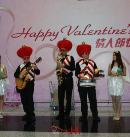 Roving three piece band with drum sax and guitar walking around Hong Kong airport wearing valentine day costumes
