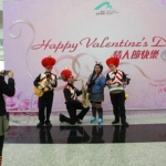 Three roving musicians dressed in red and white vests and love heart hats serenading a girl 