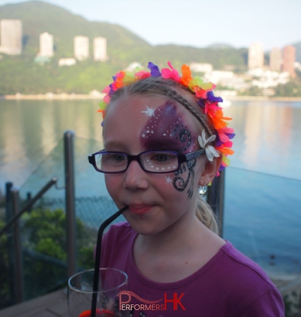 A purple sparkle half-face face paint done by a Hong Kong face painter at a family fun day