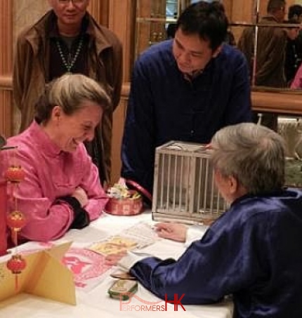 The bird fortune telling master in Hong Kong explaining the card to the guest who wearing chines traditional jacket at an annual dinner