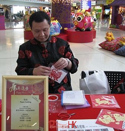 Artist in HK putting a dog zodiac paper cut out to the guest at the HKIA