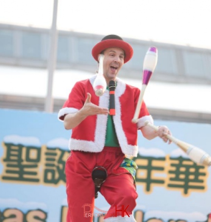 Unicyclist performing three cups juggling on the unicycle at Hong Kong Shopping center corporate Christmas Carnival event
