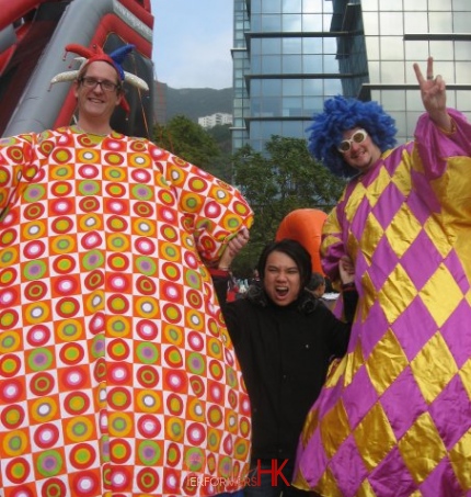 Two Hong Kong stilt-walkers squeezing a man between them at the Cycberport 