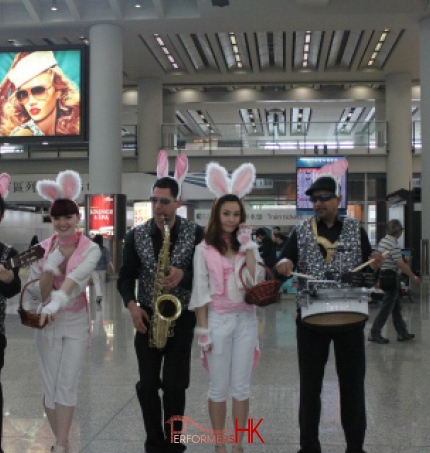 Three musician wearing bunny ears and sparkles vests , performing Easter songs with two models who dress as Easter bunny at the Hong Kong airport