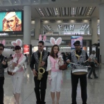 Three musician wearing bunny ears and sparkles vests , performing Easter songs with two models who dress as Easter bunny at the Hong Kong airport