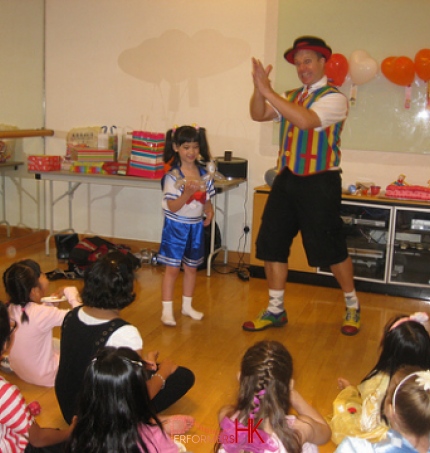 Hong Kong professional clown finished a trick with the birthday girl and he gave her a balloons as a prize to thank her at a corporate fun day event