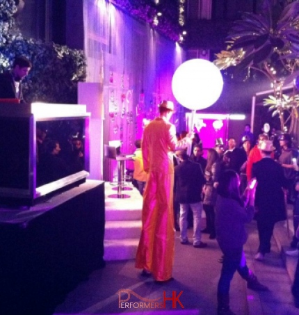 Stilt walker wearing golden costume and holding a giant chupa chup