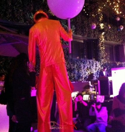 Hong Kong stiltwalker wearing a gold stilt costume taking picture with a guest at a Hong Kong night club opening event.