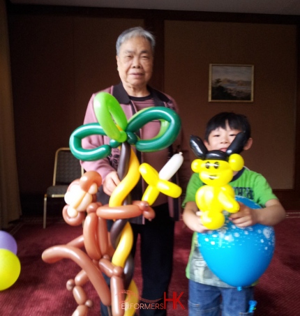 Two guests holding a giant balloons which twisted by a roving balloons artist in Hong Kong at a corporate family fun day
