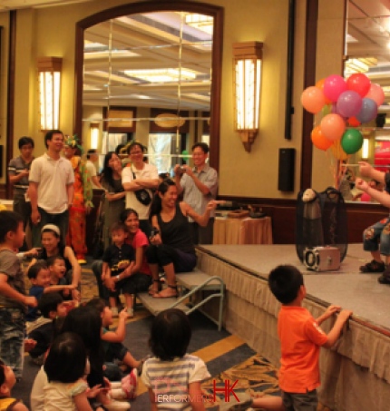 Magician on a stage at the Dynasty Club in Hong Kong doing a sponge ball routine being watched but a crowd of children