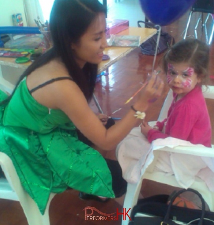 Hong Kong  professional face painter working on her lovely pink butterfly face paint for a little girl at a children birthday party