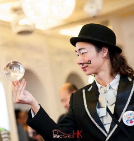 Contact juggler in HK wearing clown make up and costume performing with a crystal ball at a annual dinner