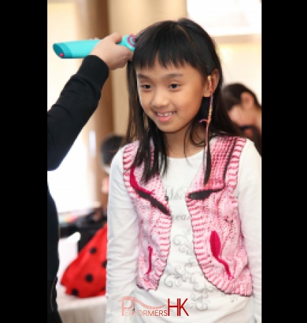 A little girl getting second braid wrap with a colorful string at a school event