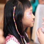 Child got a braid wrap with a colorful string at a festival event