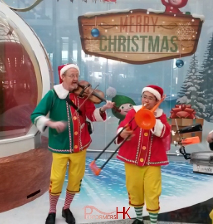 Three strolling musicians playing the violin drum and trombone at the HK Airport nest to santa in a globe 