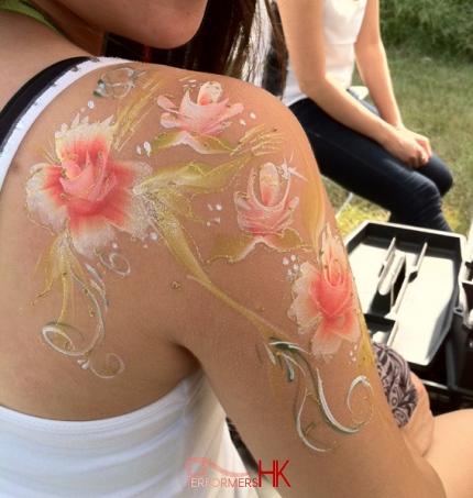 A talented face painter in HK draw an elegant flower paint on a ladys arm and back at a festive event