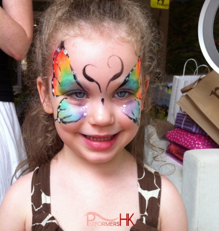 Hong Kong professional face painter draw a butterfly on a child face at a family fun day