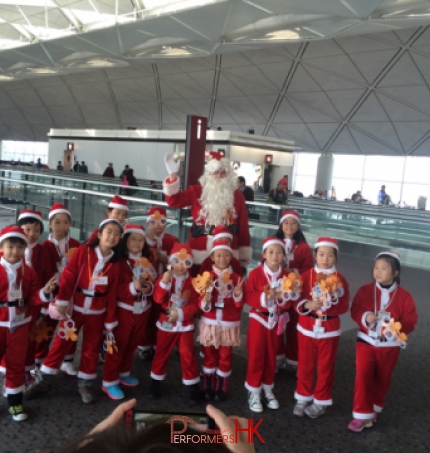 santa clause at hong kong airport with children in red santa costumes