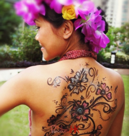 Hong Kong face painter draw a fancy flowers painting on a lady back who wearing a flower rings on head at a festive event