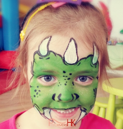 HK famous face painter draw a little green monster face paint on a girls face at a Halloween function