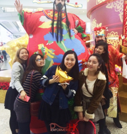 stilt-walker in Hong Kong in giant inflatable Choi Sun talking photo with normally Choi Sun and five ladies at a corporate CNY event